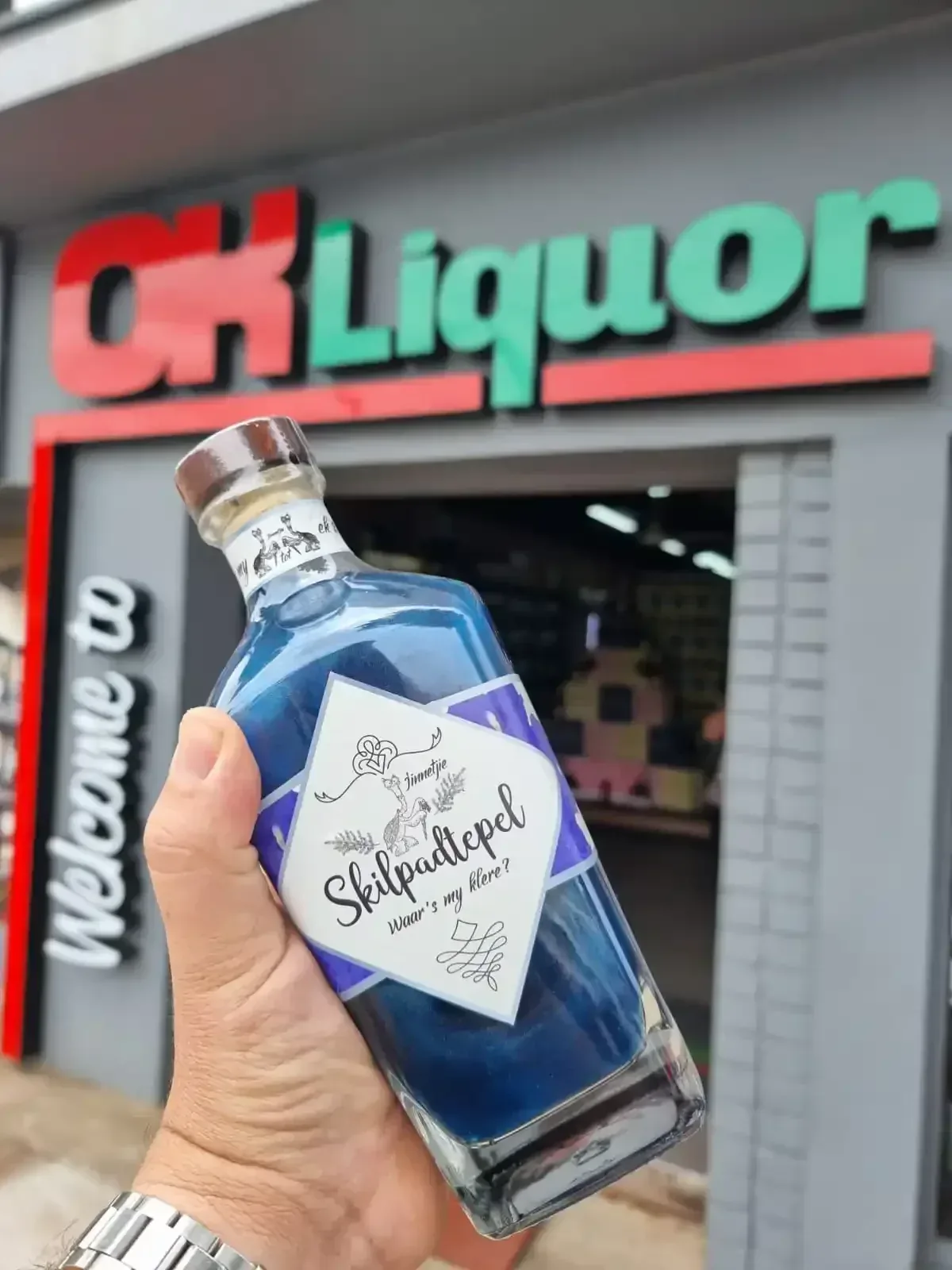 Hand hou 'n Skilpadtepel bottel met pers vloeistof voor 'n OK Liquor-winkel
